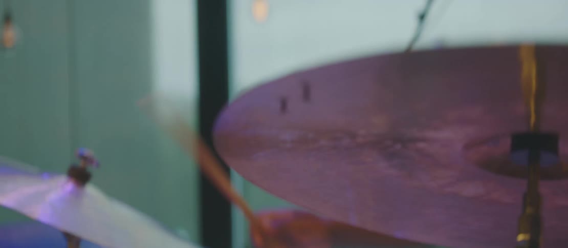 A man is playing the drums by a window