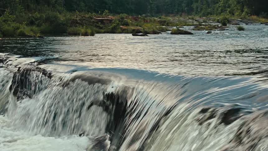 A river with water falling to a level in an area with lots of rocks on the sides
