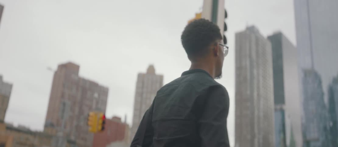 Cheerful man walking through a metropolis on a cloudy day