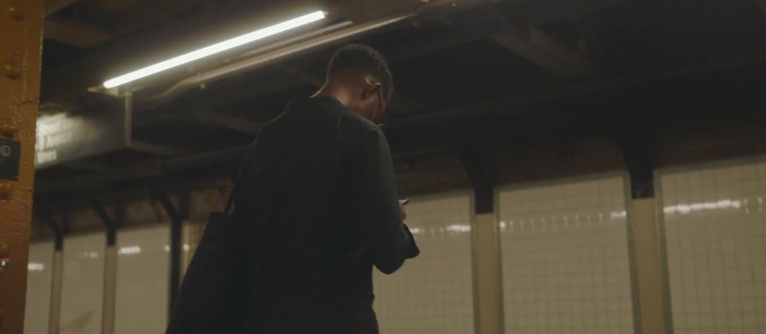 Man with a smartphone in his hands waiting standing at a subway station