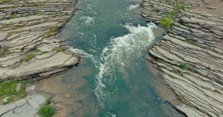 A river passes through two rapids while flowing through a forested area
