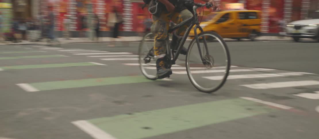 A person riding a bicycle on an asphalt street passing over a pedestrian crossing