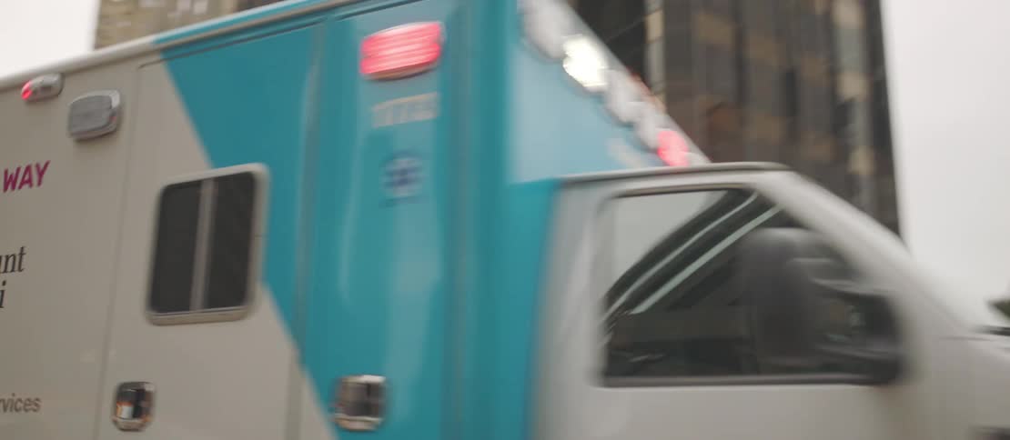 Ambulance flashes its lights while driving along a downtown street