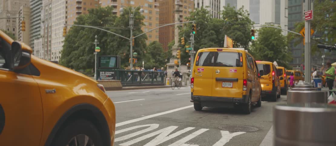 A line of taxi cabs in a bus lane waiting for the traffic sign to turn to green