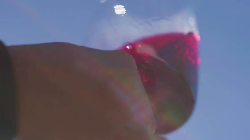 A person is shaking a glass of wine