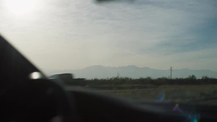 A view from inside a car of a natural landscape with mountains in the background