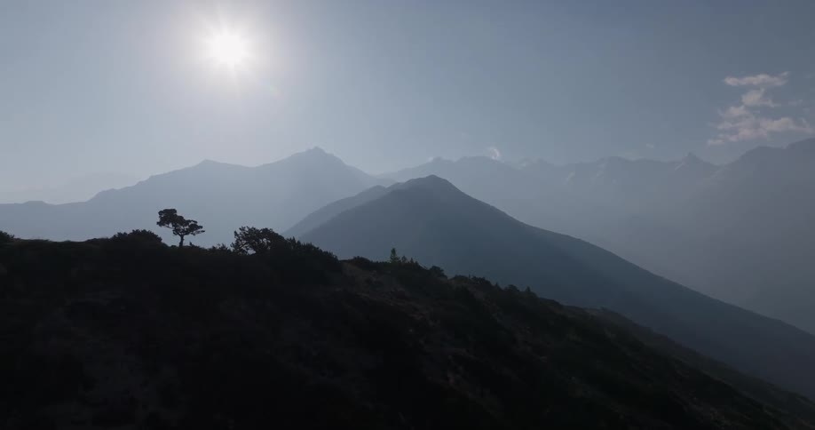 Aerial panorama of mountain ranges and the sun on the horizon