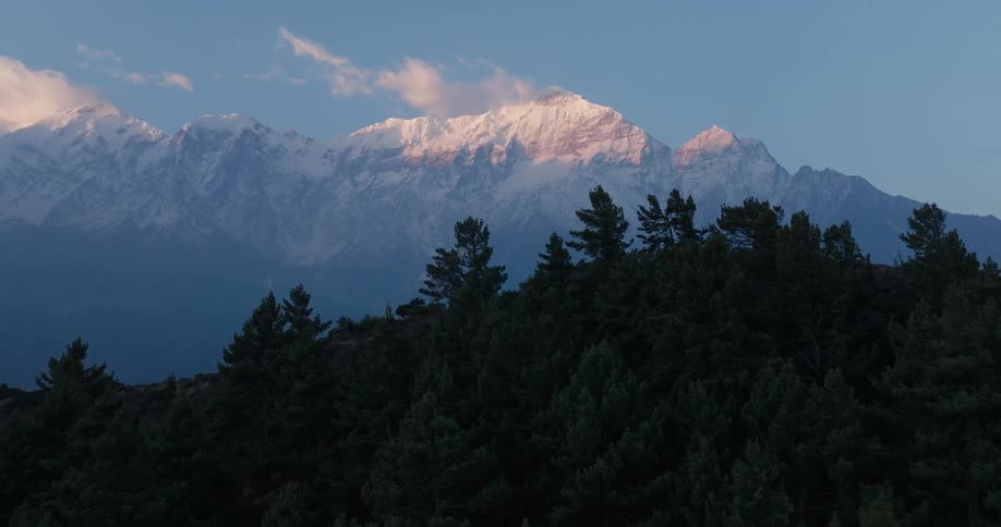 A mountain range with mountains covered by trees and snow