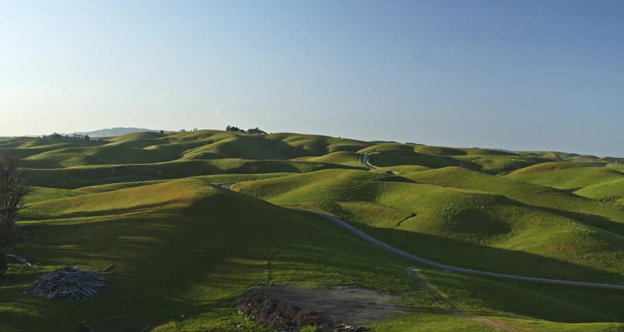 A road winds through green hills in a rural area