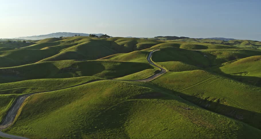 A road runs over green hills in a rural area