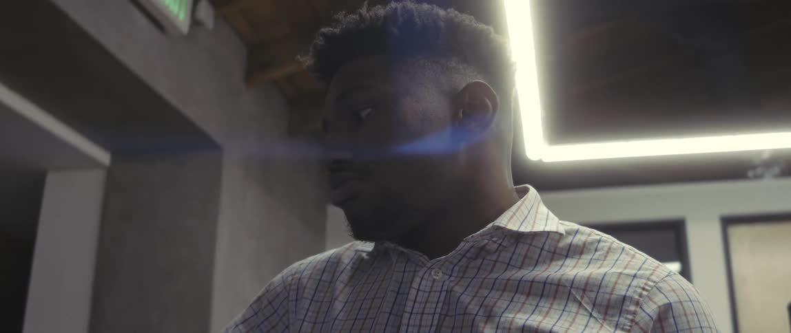 A young man in a white striped tshirt is huffing and puffing while looking straight ahead and shaking his head