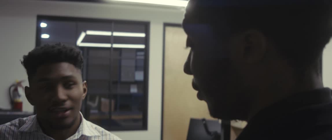 Two men in an office environment talking while standing
