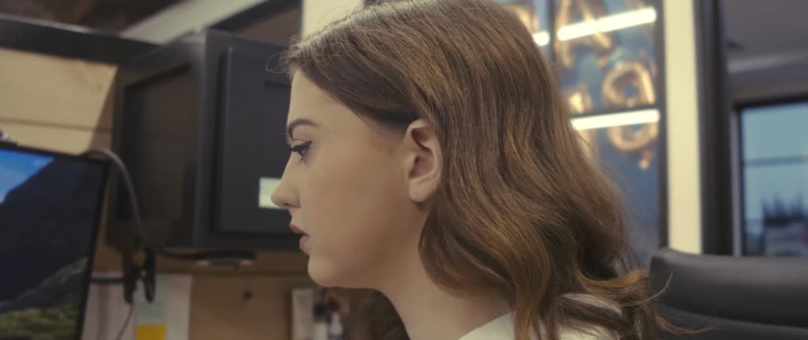 A young woman in an office cubicle picks up the phone