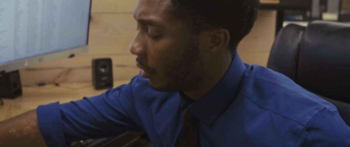A male worker smiles after hanging up the phone in his cubicle in an office
