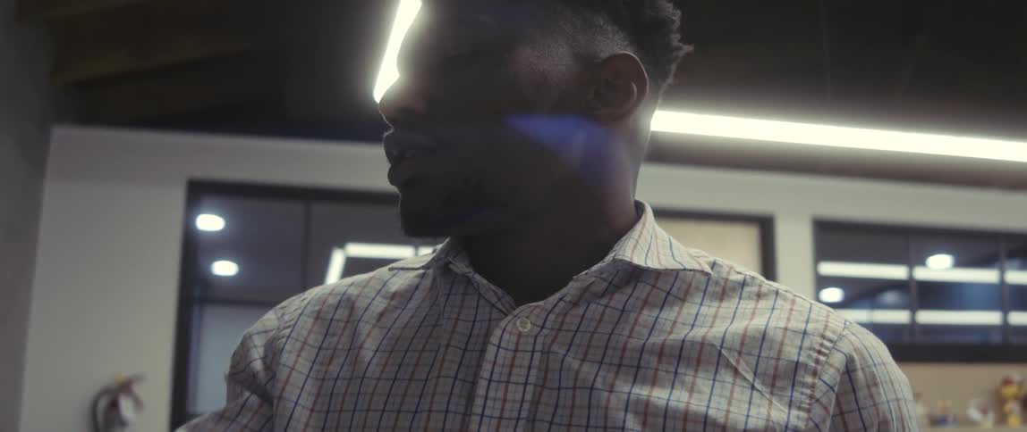 A young black man talks to himself as he works in an office