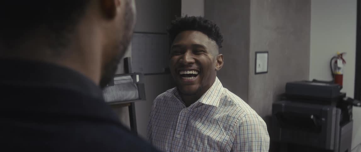 Two men standing in an office environment laughing and talking