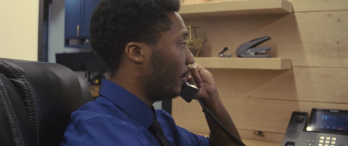 Man sitting has an office chair converted to a corded telephone