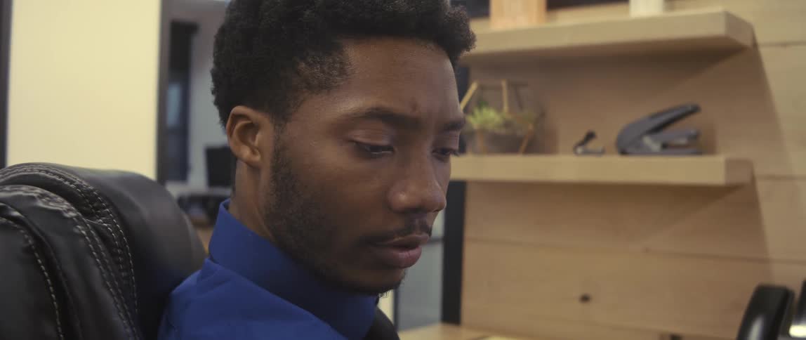 A male employee working in a cubicle acknowledges another employee walking by his cubicle