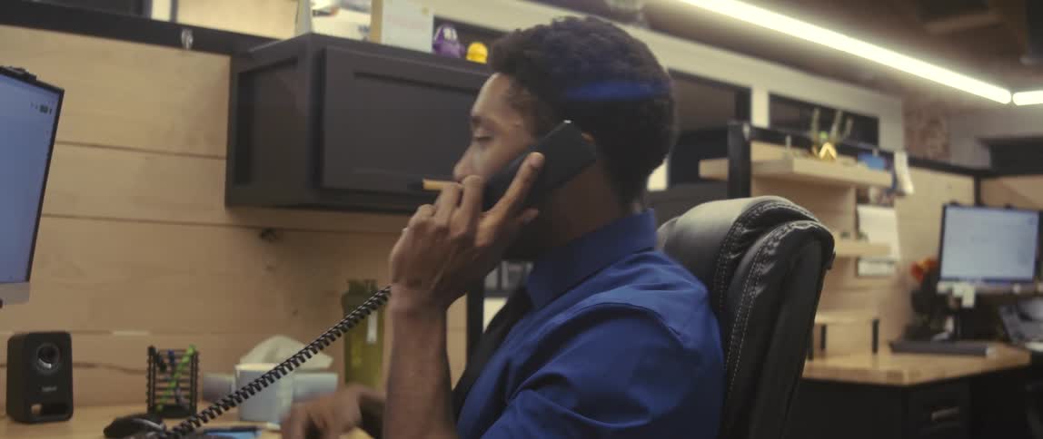 Man sitting in an office chair answering a phone call