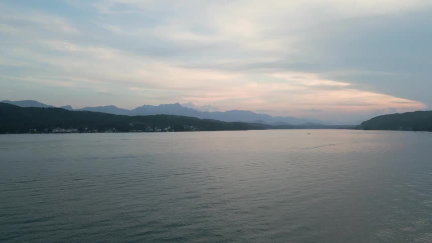 A tranquil body of water with gentle ripples and a mountain range in the background