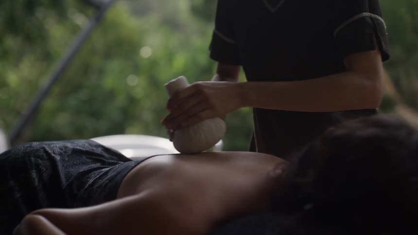 Womans hands holding an object and massaging a persons back