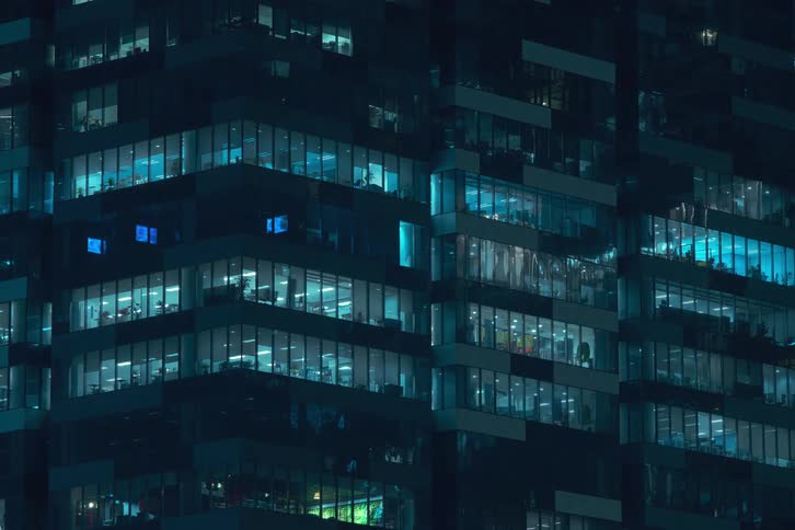 A modern office building at night illuminated by blue lights in its windows
