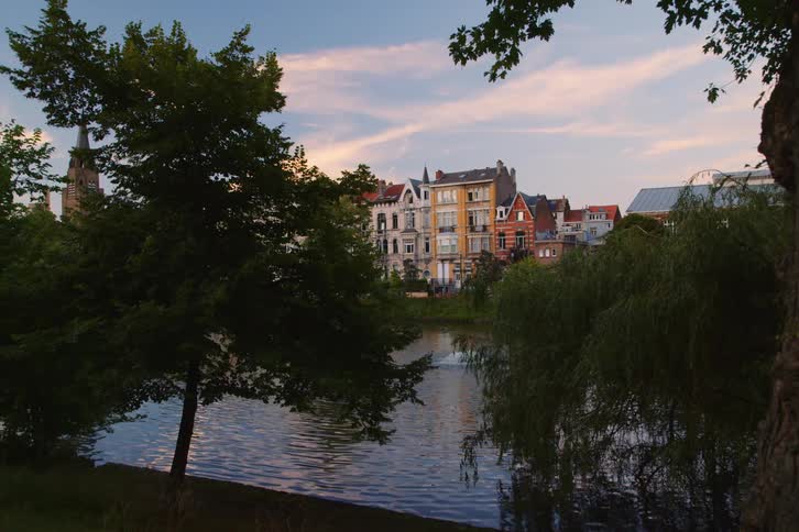 A serene view of a water body with reflections of adjacent buildings and trees at dusk