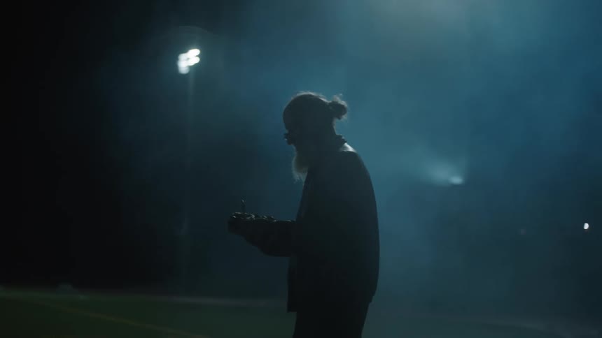 A man walks on the track by the field at night