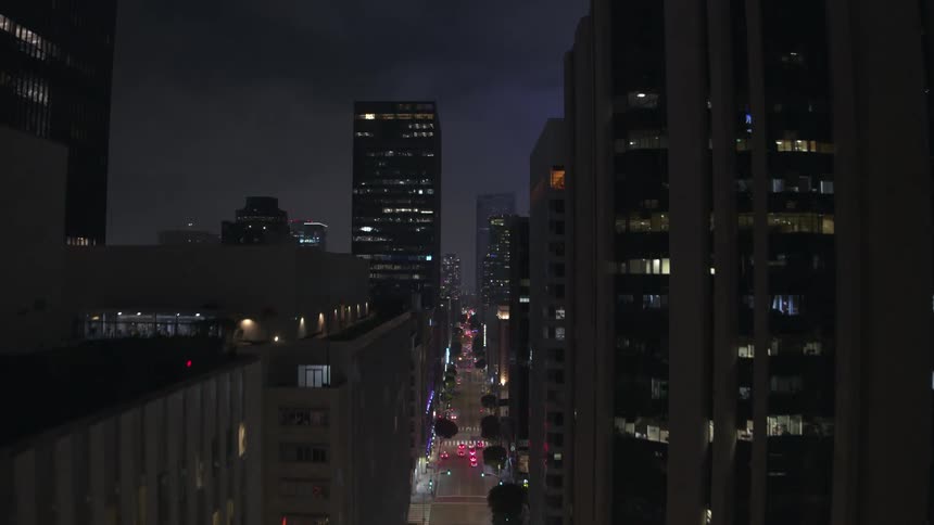 A night time cityscape with illuminated buildings and a long avenue lined with lights