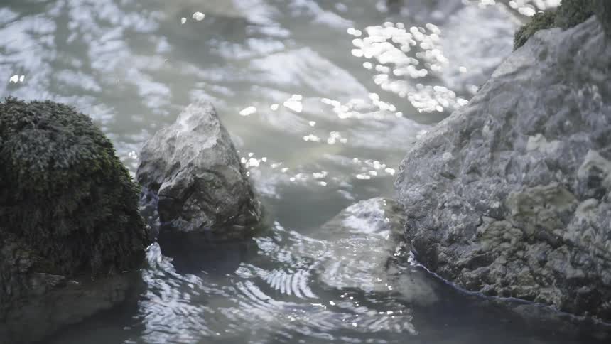 A closeup view of water flowing between two mosscovered rocks