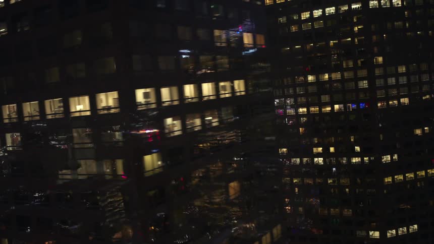 The tall office buildings are brightly lit at night