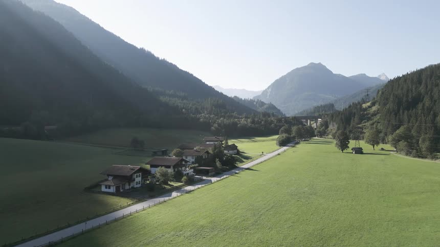 Aerial panorama of houses in a rural setting surrounded by mountains and vegetation
