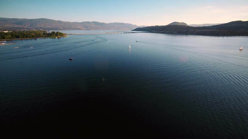 An aerial view of a large lake with some boats sailing on it and there is strong sunlight coming from above