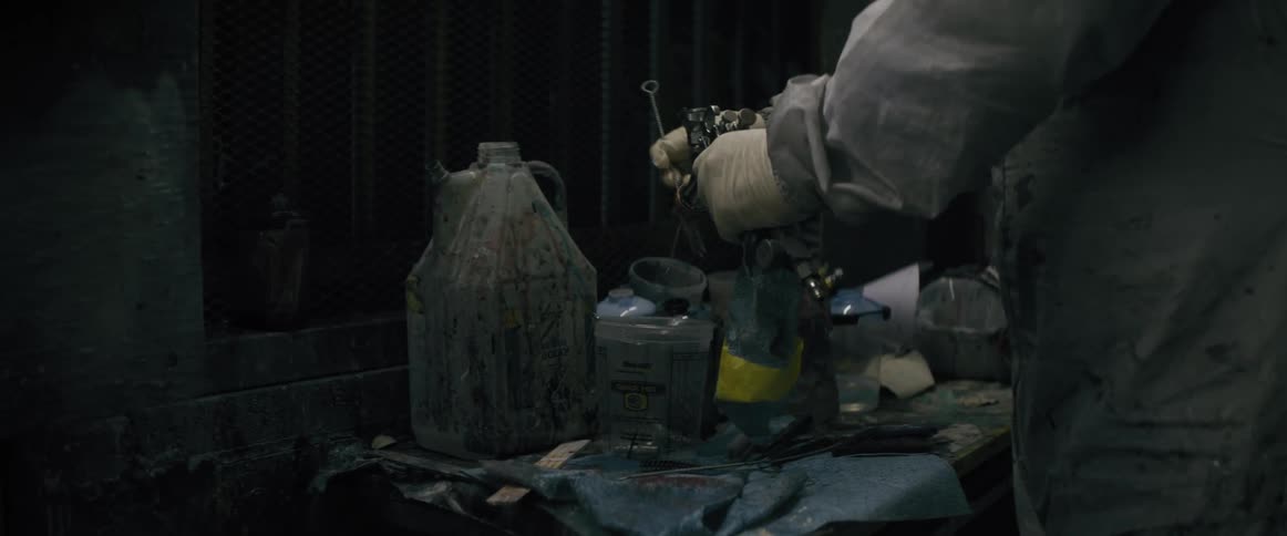 A person is cleaning a paint sprayer with a brush
