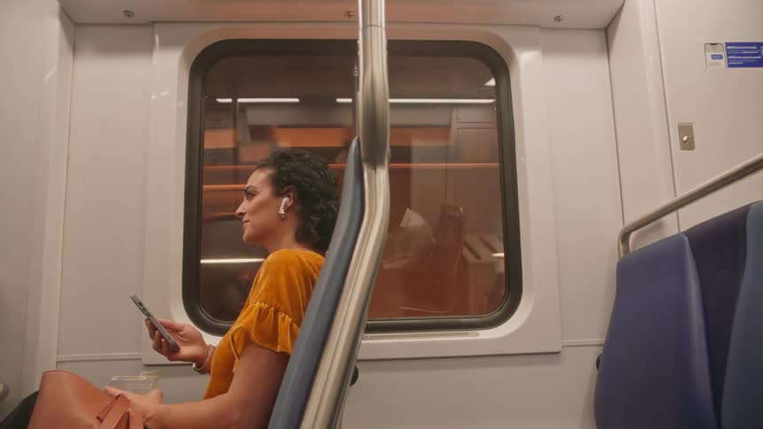 Woman sitting on a moving train using her smartphone