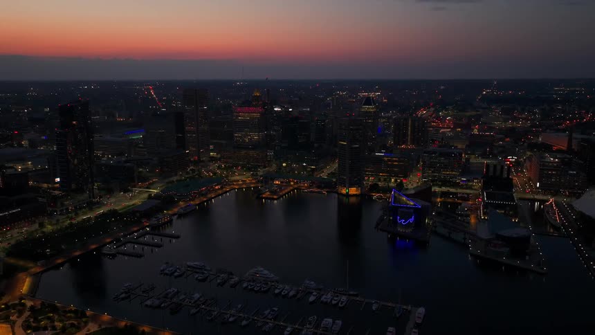 An aerial view of a city skyline at dusk with a harbor and boats