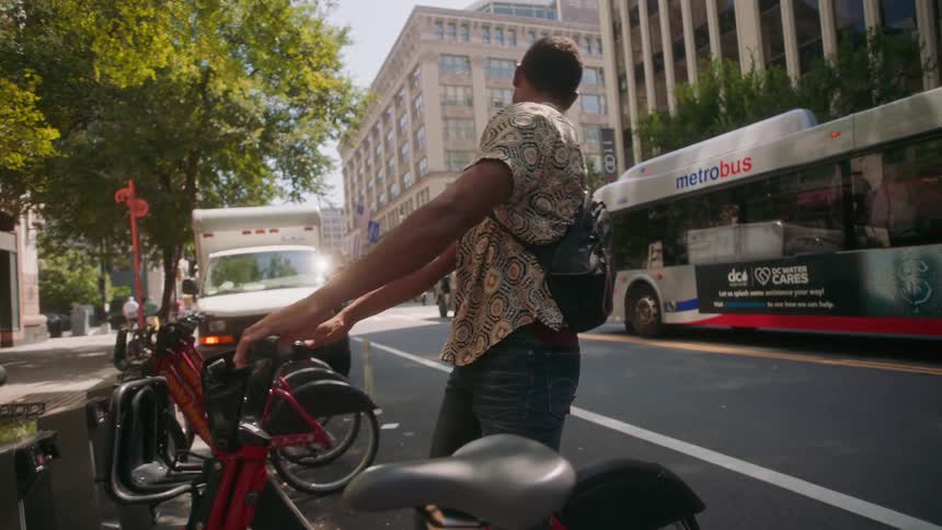 Man renting a bicycle and riding through the streets of a metropolis