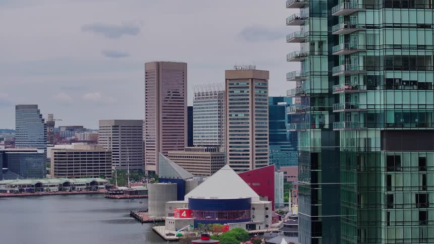 A skyscrapers gives way to smaller city structures sitting on a coastline