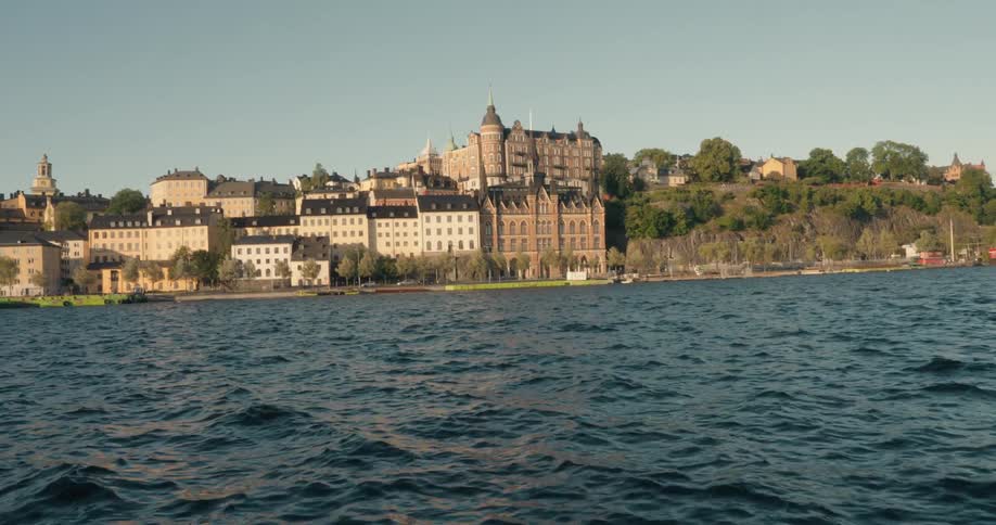 Several large old buildings facing the water of a large lake with many waves