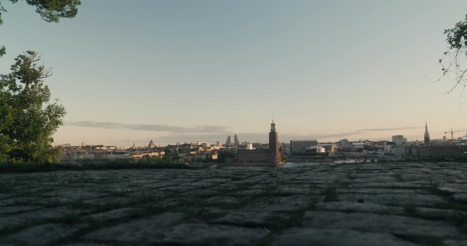 Panorama of a classic metropolis and the sky with orange tones on the horizon and cobblestones in the foreground