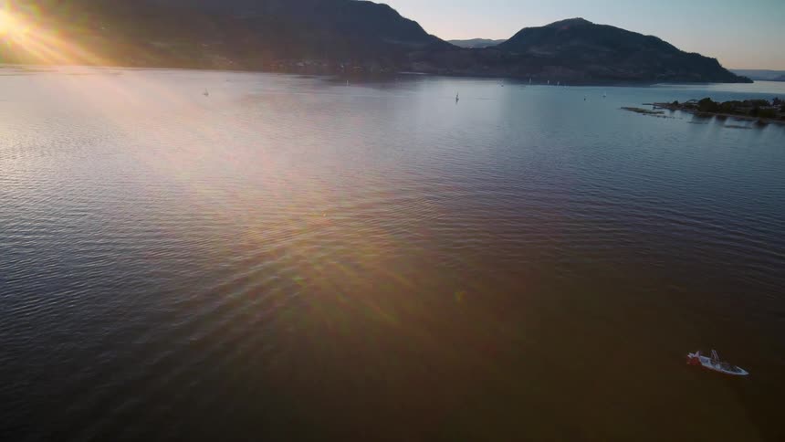 A serene lake with gentle ripples surrounded by mountains and a clear sky at morning