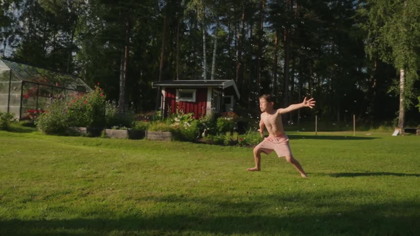 Boy playing with soap bubbles and a yard with trees in the background