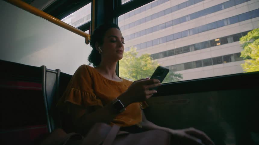 A woman looks at her phone as she rides on the train