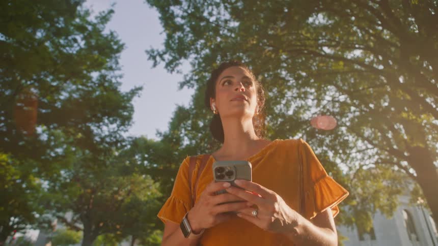 Female pedestrian keeps looking down at her cellphone while walking