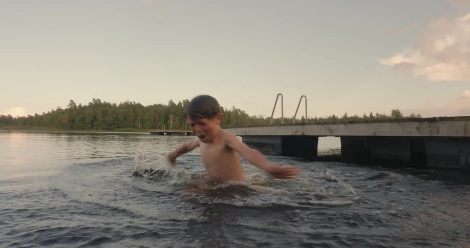 Little boy jumping into a lake