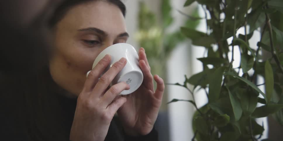 Woman drinking coffee next to a man