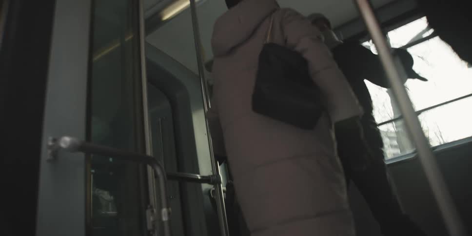 Three people step into a city bus on a cloudy winter day