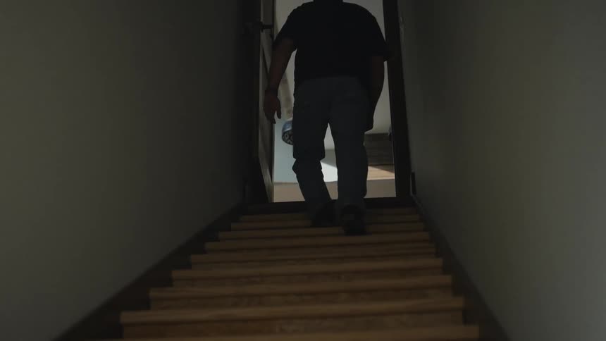Silhouette of a person ascending a dimly lit staircase