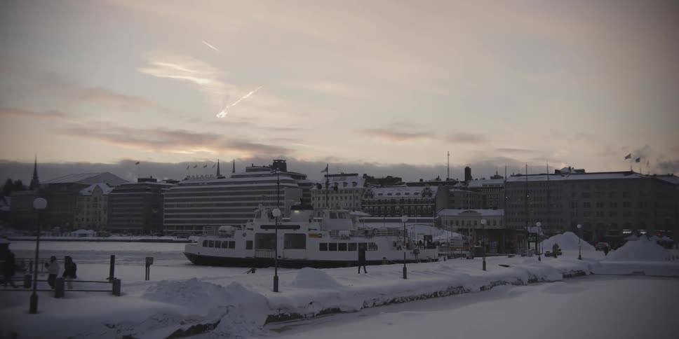 A ferry is docked in a snowy harbour in a city skyline