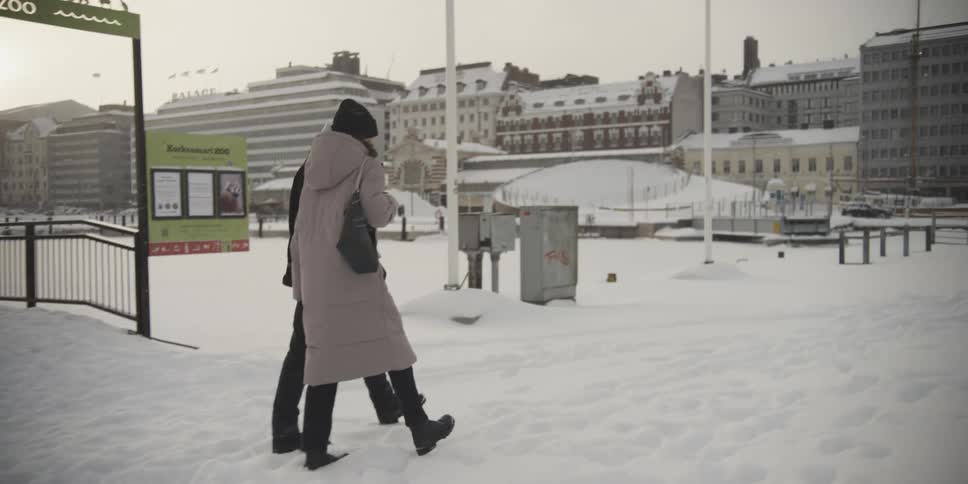 Couple walking through a snowcovered square in a city